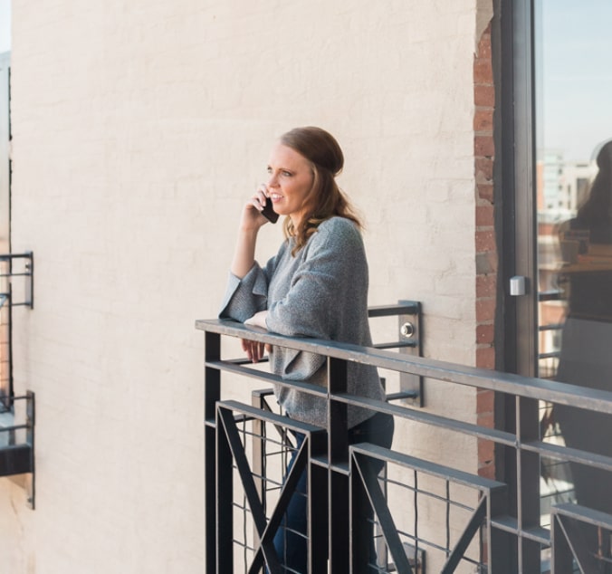 Becca making a call on a balcony.